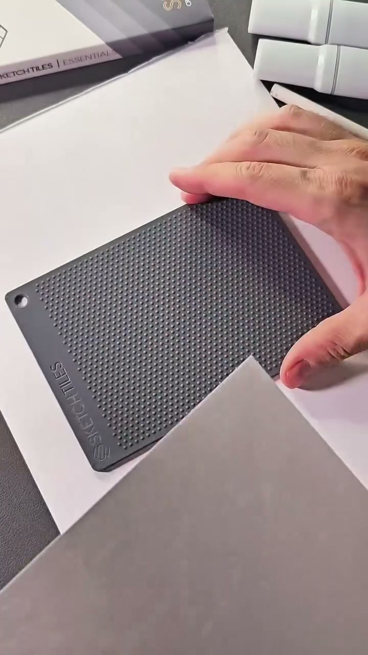 Isometric Dot Grid Tile on the desk as the paper is lifted for placement.