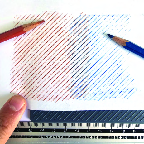 Red and blue diagonal pencil marks extend across the paper, with a tile aligned against a ruler beneath it.